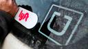 In this 2018, file photo, a Lyft logo is installed on a car next to an Uber sticker in Pittsburgh. In this 2018, file photo, a Lyft logo is installed on a car next to an Uber sticker in Pittsburgh.