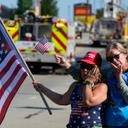 Merri Cambo of Saxonburg, Pa., and her friend, Jane Wesolosky, of Buffalo, Pa., react as the funeral procession for Corey Comperatore passes by July 19 in Sarver, Pennsylvania.