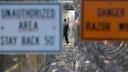 A Pennsylvania prison staffer walks in an area surrounded by fencing, barbed wire, and warning signs.