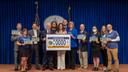 Attendees pose at a 2024 Harrisburg event celebrating a license plate featuring the state amphibian.