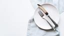A stock image of an empty plate and cutlery on a white table. A stock image of an empty plate and cutlery on a white table.