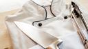 A stock image of a chef's coat and tongs on a wooden board. A stock image of a chef's coat and tongs on a wooden board.