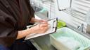 A stock image of a person with a clipboard in a kitchen. A stock image of a person with a clipboard in a kitchen.
