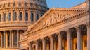 Close-up of the U.S. Capitol dome and an ornate portico illuminated by warm sunlight against a blue sky. Close-up of the U.S. Capitol dome and an ornate portico illuminated by warm sunlight against a blue sky.