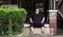 Mike Ramsey sits on the front porch of his house.