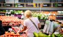 A woman browses produce at a grocery store.