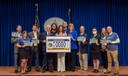 Attendees pose at a 2024 Harrisburg event celebrating a license plate featuring the state amphibian.