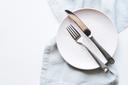 A stock image of an empty plate and cutlery on a white table A stock image of an empty plate and cutlery on a white table