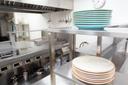 A stock image of plates stacked on a stainless steel shelf in a kitchen A stock image of plates stacked on a stainless steel shelf in a kitchen
