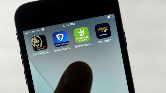 FanDuel, DraftKings, and other online gambling apps are displayed on a phone. FanDuel, DraftKings, and other online gambling apps are displayed on a phone.