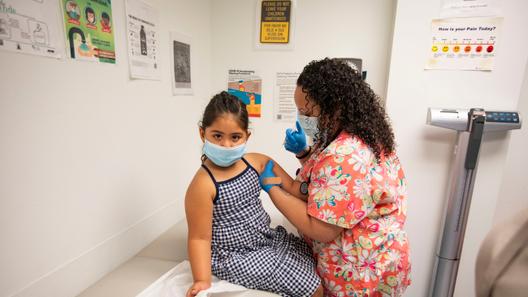 A child receives a vaccine from a nurse. A child receives a vaccine from a nurse.
