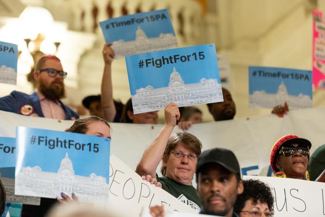 People hold up signs during a press conference and rally in 2019 calling for a $15 minimum wage.