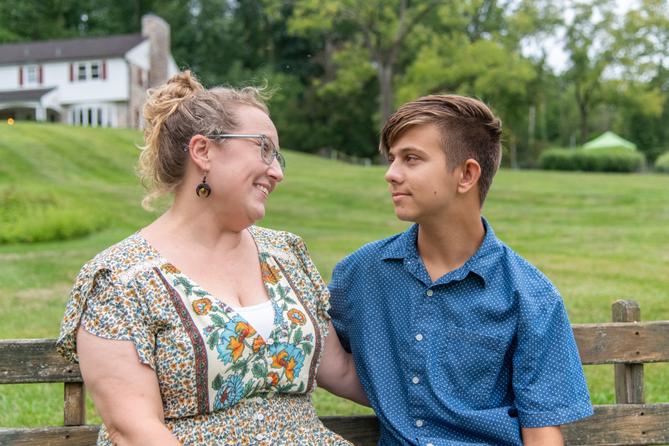 Niki Burawski and her son, Dylan, look at each other while sitting on a bench outside.