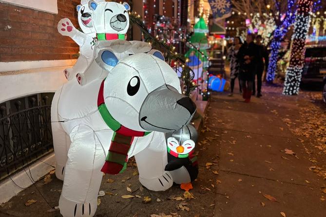 A glowing inflatable decoration of a polar bear with two cubs on its back and a penguin hugging its leg.